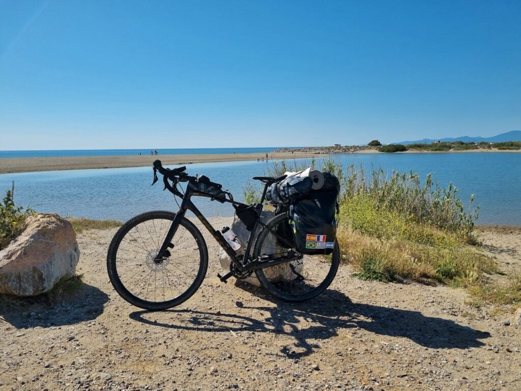 Bicycle with travel gear on a scenic coastal path in France under a clear blue sky.