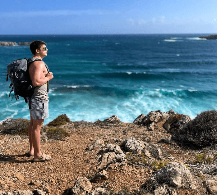 Wanderung an einer felsigen Meeresküste mit Rucksack und Blick auf den Ozean